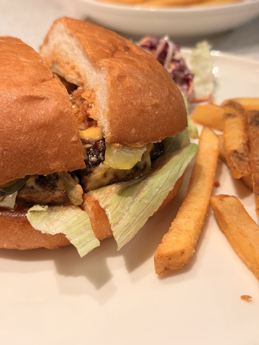 Close-up of a grilled burger with cheddar, pickles and iceberg lettuce, with fries and slaw at the All American Diner Hyderabad