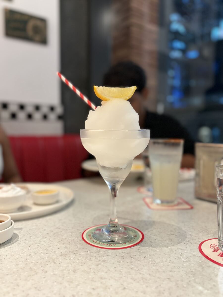 Frozen cocktail topped with a lemon wedge and a red-and-white striped straw at the All American Diner Hyderabad