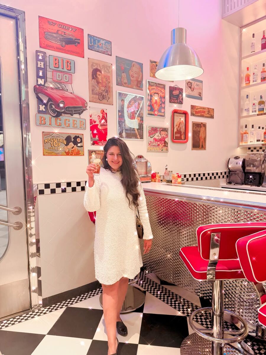 Reema of One Punjabi Binger at the counter of the All American Diner Hyderabad with red bar stools and vintage tin signs