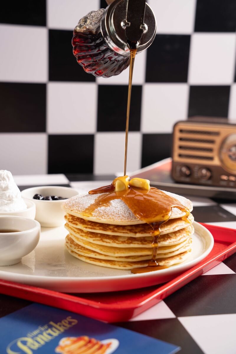 Stack of pancakes with butter and maple syrup being poured at the All American Diner Hyderabad