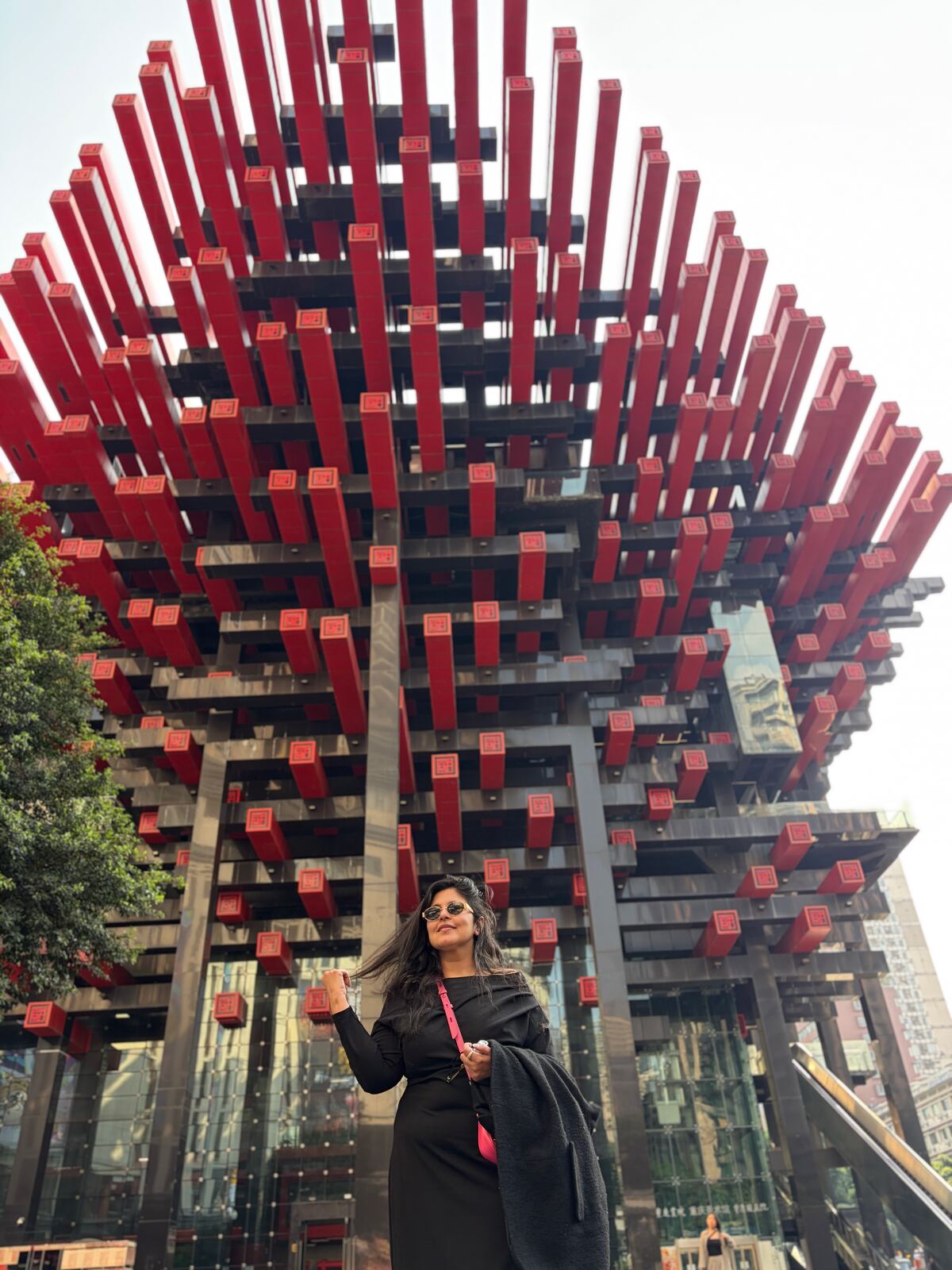 Reema in black in front of the red Guotai Arts Center, the Chopsticks Building, in Jiefangbei, Chongqing