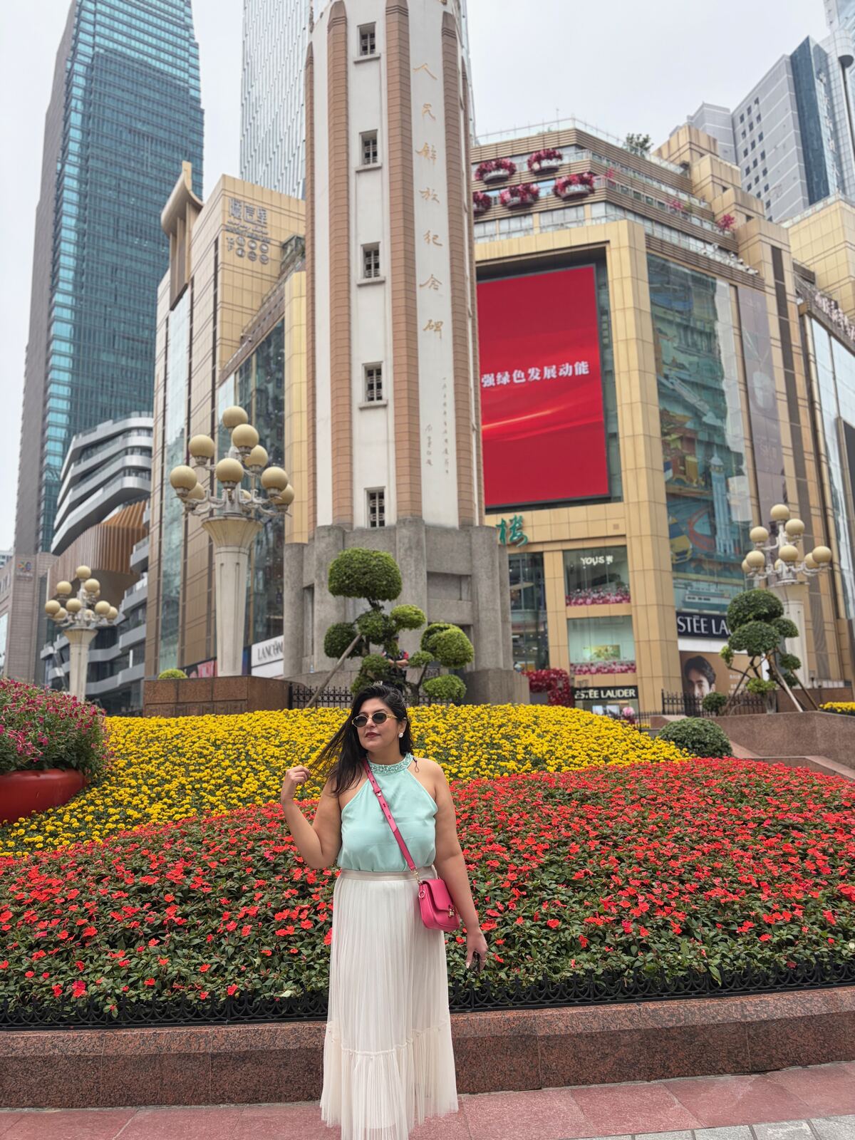 Reema standing in front of a flower bed near the Liberation Monument in Jiefangbei, Chongqing