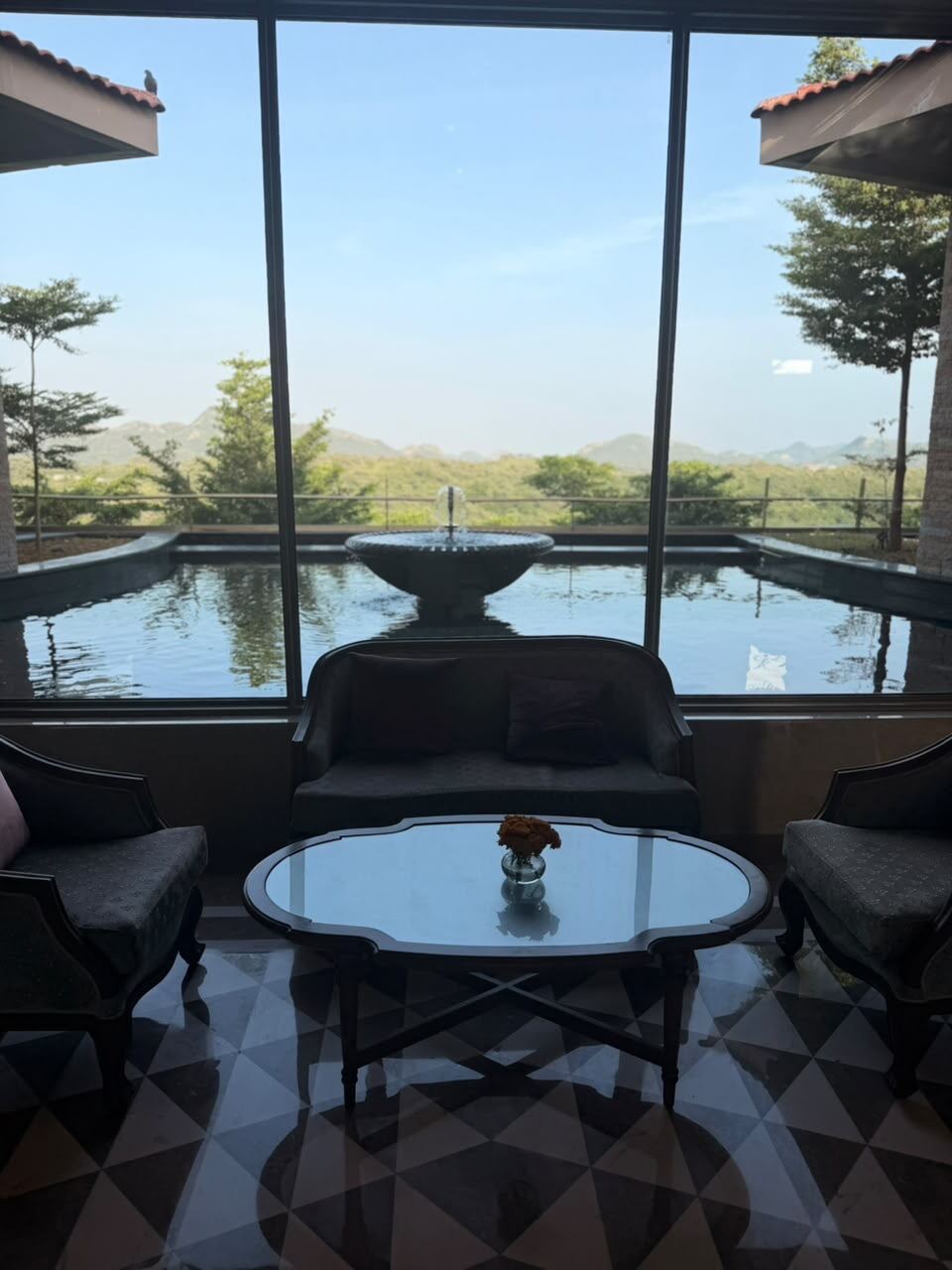 Lounge seating with a view of a fountain pond and the Aravalli hills at Mementos Ekaaya Udaipur