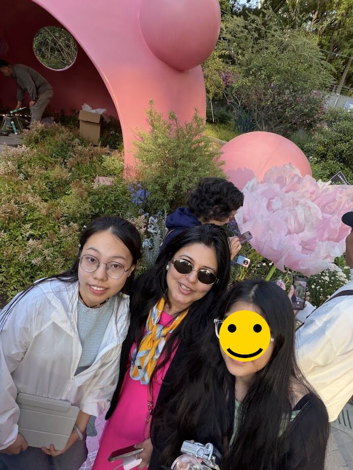 Athena, Reema and her daughter in front of a giant pink flower art installation in Shanghai