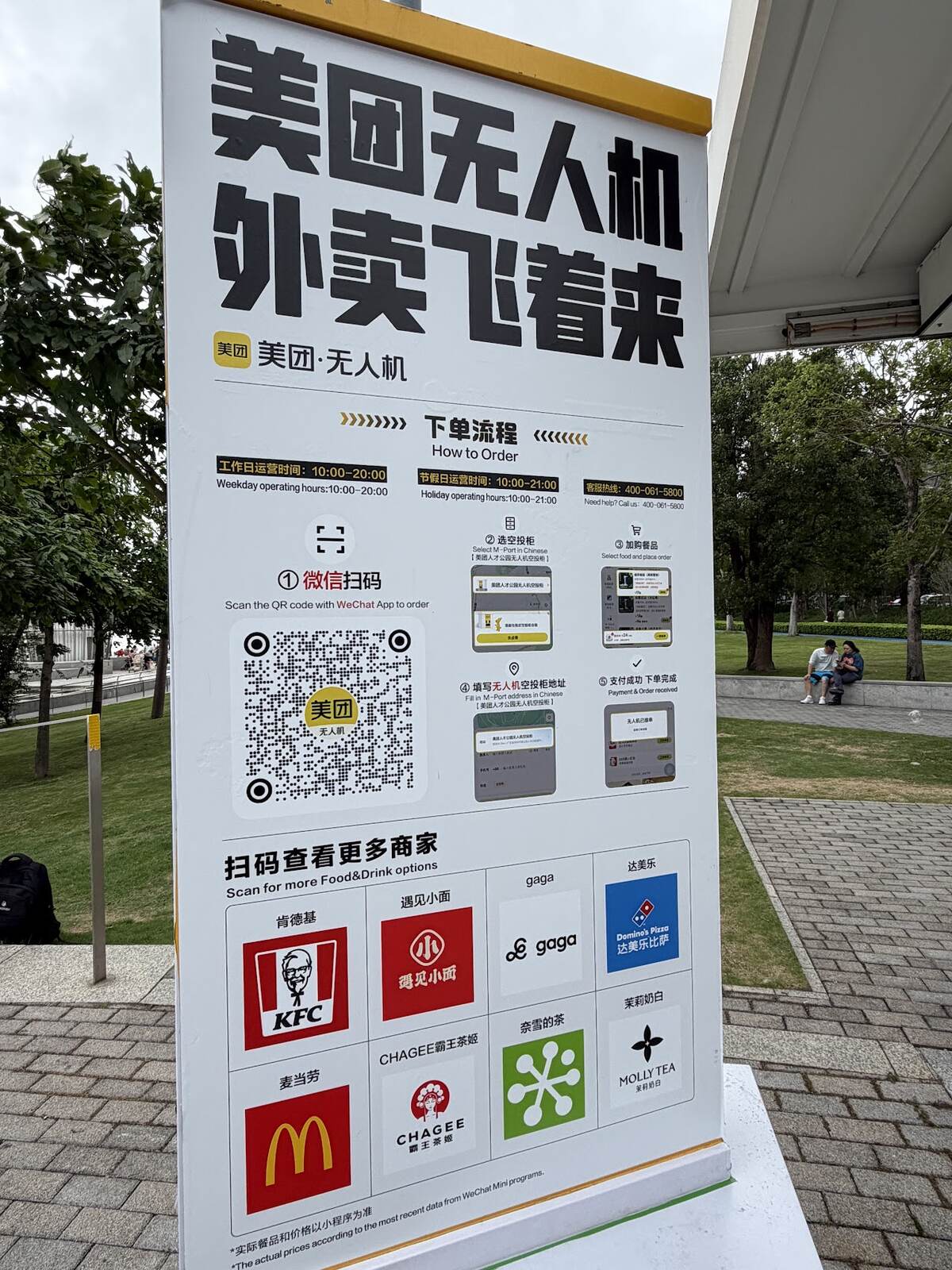 Meituan drone delivery how-to-order signage at Shenzhen Talent Park showing QR code, steps, and available food brands including KFC, McDonald's and Domino's