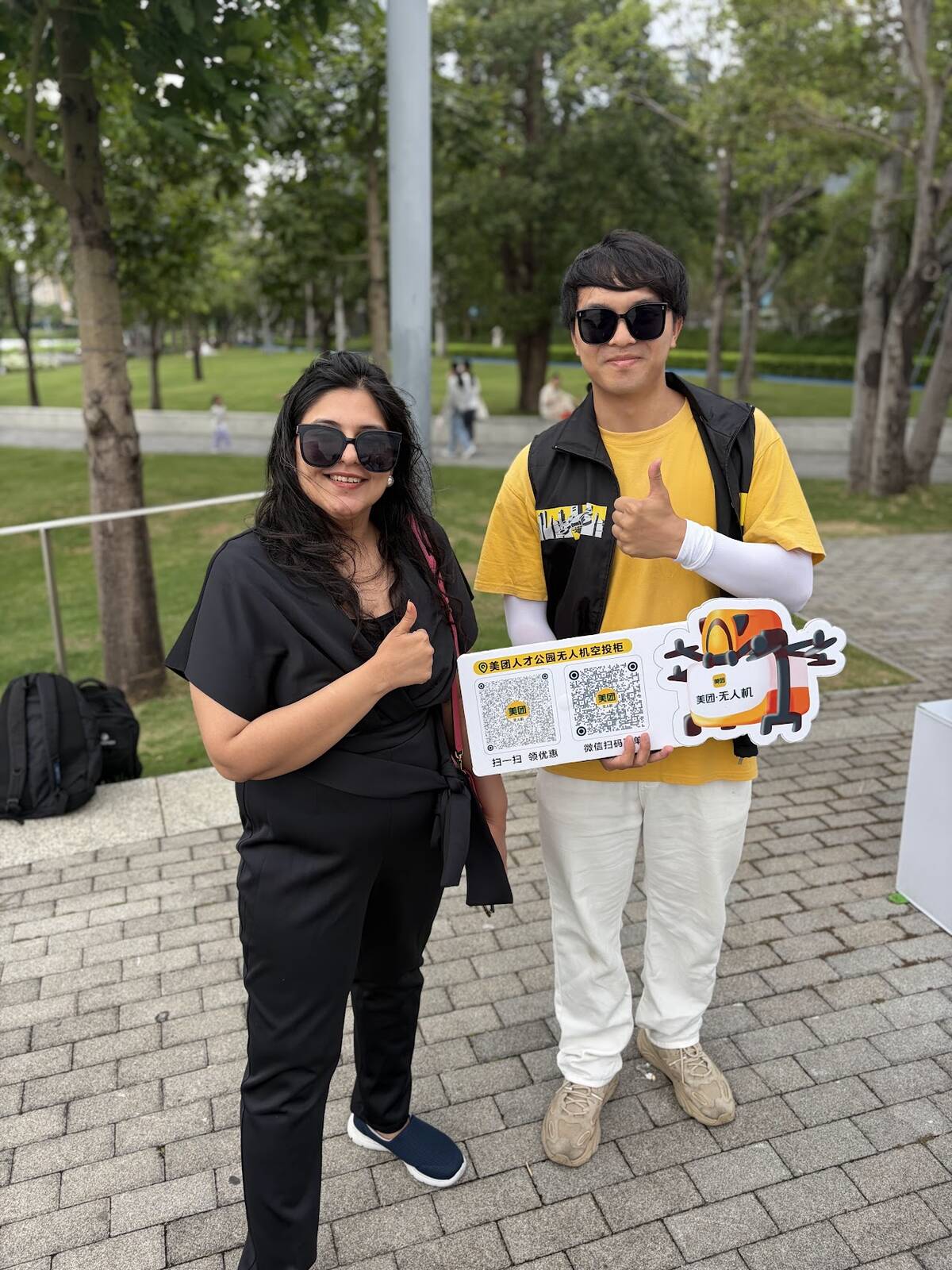 Meituan staff member in a yellow vest helping place a drone delivery order at the Shenzhen Talent Park kiosk